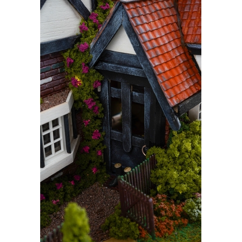 410 - A scale model diorama of a Tudor cottage with garden and streams in the style of Lilliput Lane, fitt... 