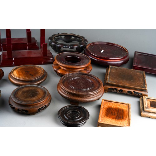 210 - A collection of seventeen late 19th / 20th century Oriental wooden display stands, various shapes an... 