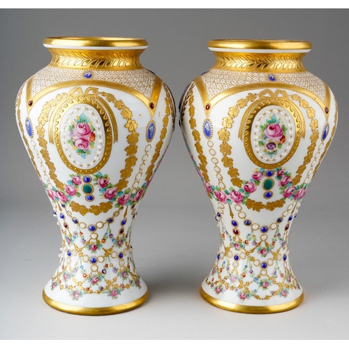 64 - A pair of early 20th Century Vienna porcelain vases, each profusely decorated with gilt and painted ... 