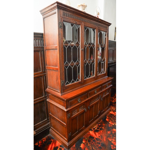 380 - An Old Charm carved oak reproduction display cabinet, the upper section with leaded cupboards, the l... 