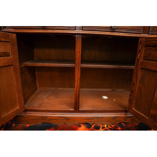 380 - An Old Charm carved oak reproduction display cabinet, the upper section with leaded cupboards, the l... 