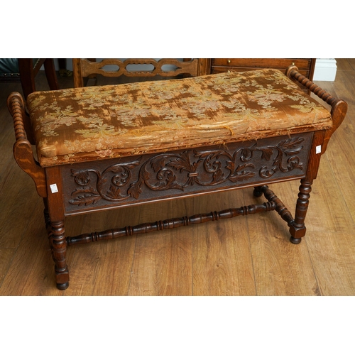 392 - A Jacobean Revival carved oak rectangular bench / piano stool, bobbin turned handles above carved ap... 