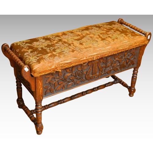 392 - A Jacobean Revival carved oak rectangular bench / piano stool, bobbin turned handles above carved ap... 