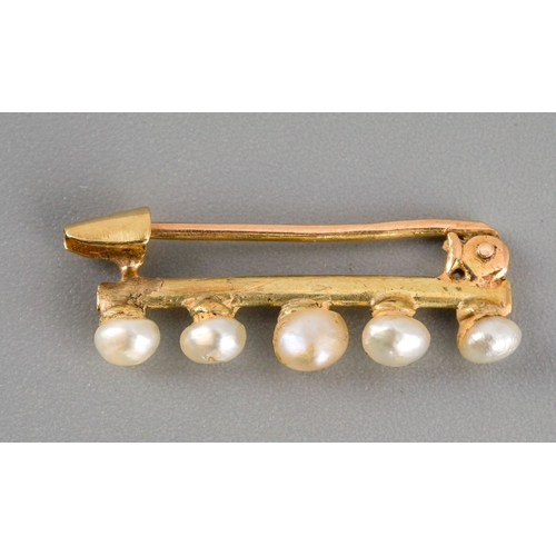 591 - An Edwardian gold seed pearl bar brooch. Te knife edge yellow metal brooch set with five seed pearls... 