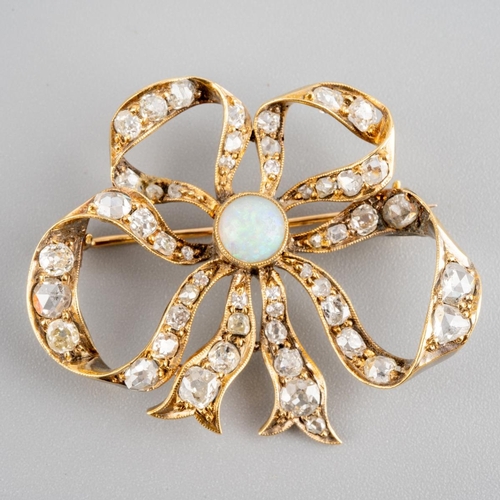 A late 19th century 18ct gold opal and diamond bow brooch. Set with an opal cabochon, measuring approx 5.7mm, within a millegrain border, to the old cut and rose cut diamond double bow, diamonds measuring from approx 3.4 mm to 1.4mm, approx length 39mm, some light abrasion to surface of opal, gross weight 8.29 grams.
