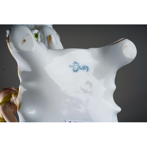 15 - A pair of Dresden Sitzendorf figural candelabra., the urn shaped sconces on scroll branches applied ... 