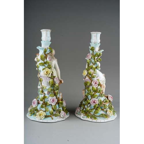 17 - A pair of early 20th Century Sitzendorf candlesticks modelled as seated Classical Maidens, tulip sha... 