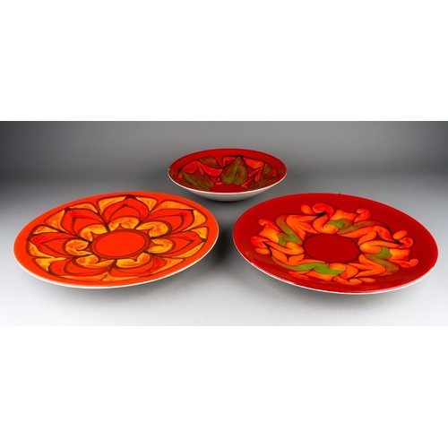 56 - Two Poole Pottery Delphis chargers, shape no 5, one in red, orange and green colourways, the other i... 
