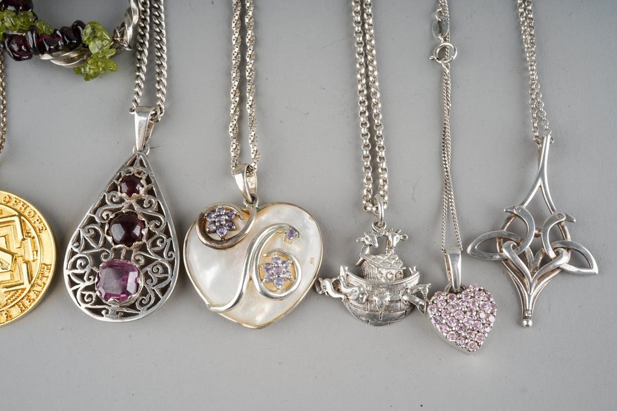A collection of white metal pendants and chains including some examples ...
