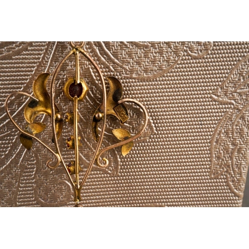 29 - An early 20th century 9ct gold gem set pendant and chain. The scroll design pendant set with garnets... 