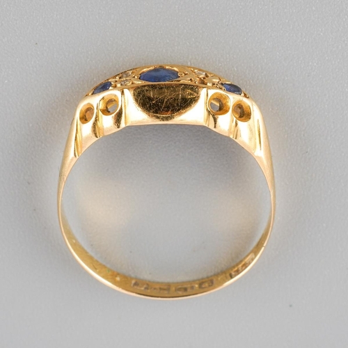 50 - An Edwardian sapphire and diamond ring. Set with a principal circular shape sapphire, flanked to eac... 