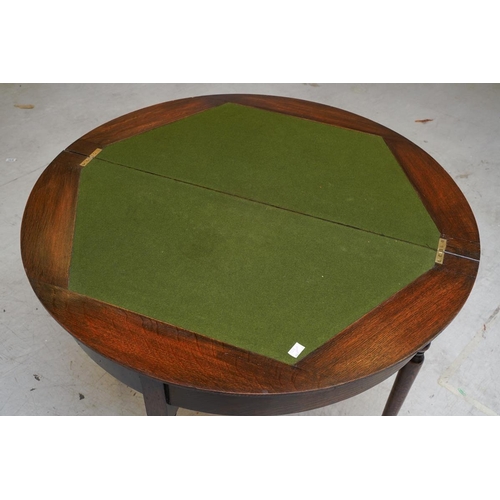 59 - An early 20th century dark stained oak demi lune card table, the fold over top with baize lining, on... 