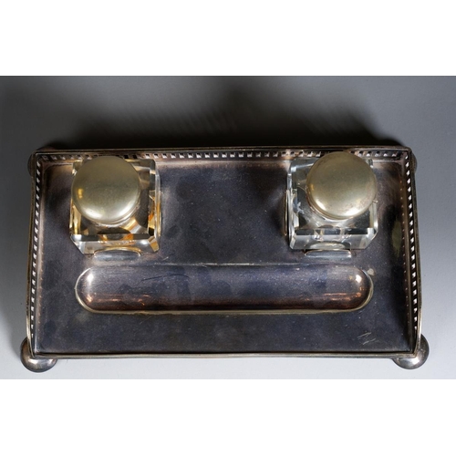 386 - An early 20th Century silver plate inkwell with gallery rail on bun feet with a pair of glass inkbot... 