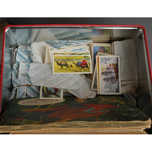 699 - A tin containing various post cards and albums of tea cards and two albums of early 20th century and... 