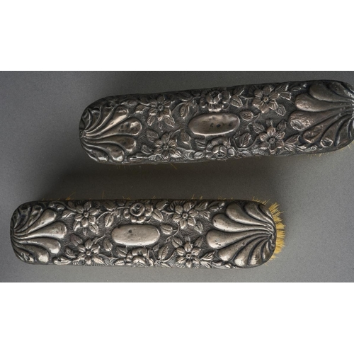 1028 - A pair of later Victorian silver mounted clothes brushes, chased with flowers and shell, hallmarked ... 