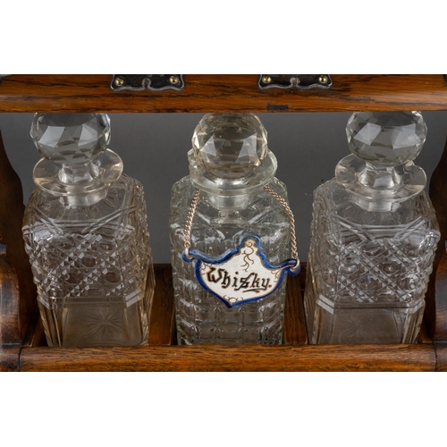 651 - A late 19th century Walker and Hall EPNS mounted oak tantalus, fitted with three square decanters, o... 