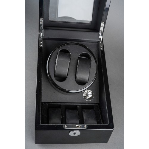 15 - A black finish automatic watch winding case for two watches, the glazed hinged sloped front enclosin... 