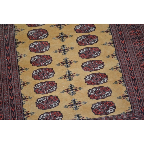 7 - A red and gold ground Bokhara style rug - Approx 5ft 10