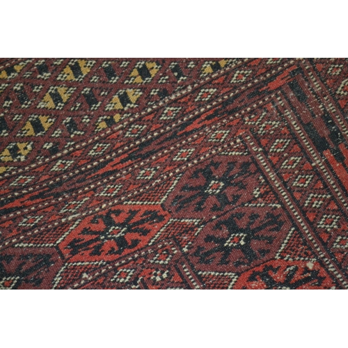 7 - A red and gold ground Bokhara style rug - Approx 5ft 10