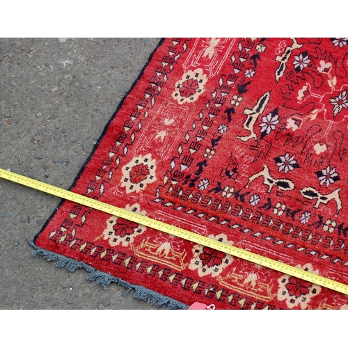 28 - A vintage red rug decorated with animals