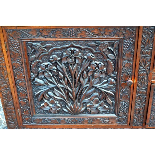 222a - An antique carved wooden Anglo-Indian sideboard decorated with vines and Lotus flowers and a snakesk... 