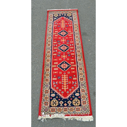 122 - A large red ground hall runner rug