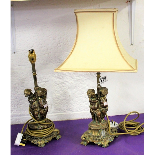 286 - A pair of gilt metal table lamps formed as cherubs - one with shade - Postage/packing not available