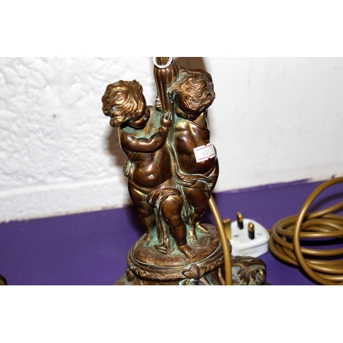 286 - A pair of gilt metal table lamps formed as cherubs - one with shade - Postage/packing not available