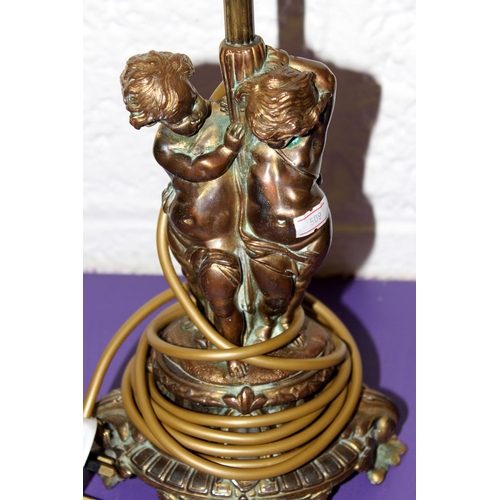 286 - A pair of gilt metal table lamps formed as cherubs - one with shade - Postage/packing not available