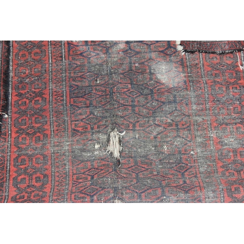 204 - An antique red ground rug decorated with and optical illusion of repeating gul - purchased from Harr... 