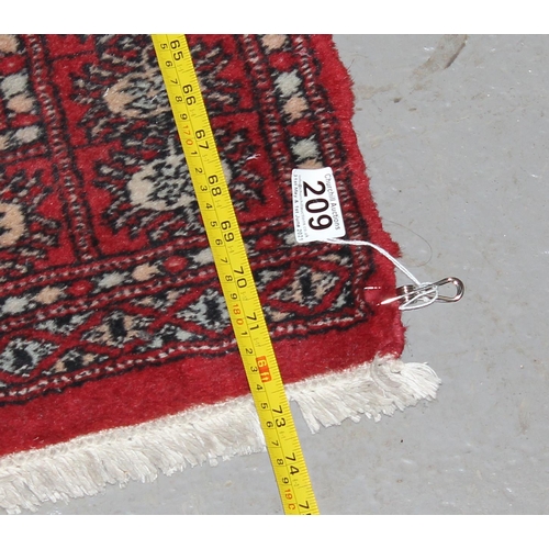 209 - A red ground runner rug, believed to be hand made decorated with gul medallions - likely Afghan