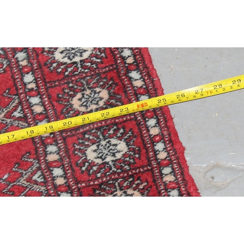 209 - A red ground runner rug, believed to be hand made decorated with gul medallions - likely Afghan