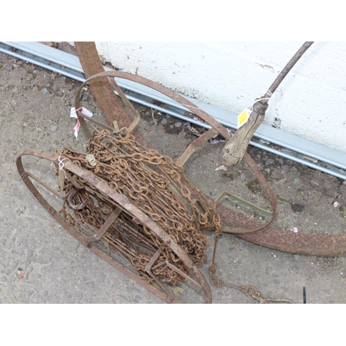 452 - A chain of chain on a reel, antique cast iron cartwheel rim and a harvesting tool