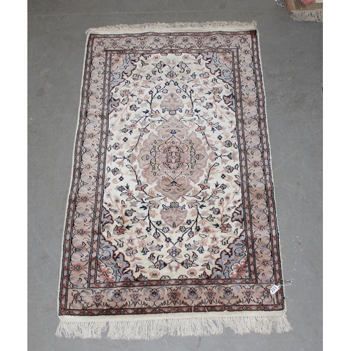 223 - A cream ground rug decorated with Arabesque patterns - believed to be of Pakistani origin with hand-... 