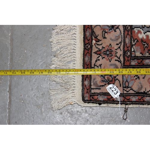 223 - A cream ground rug decorated with Arabesque patterns - believed to be of Pakistani origin with hand-... 