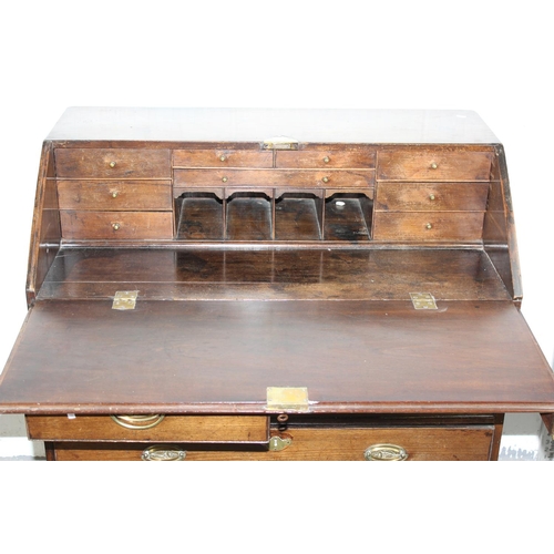 62 - A Georgian Oak bureau standing on bracket feet with brass handles