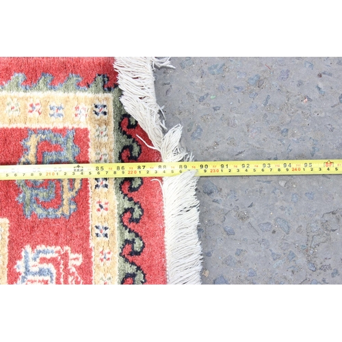 214 - A cream and red ground rug and a black and white squares rug