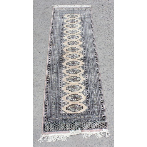 215 - A long runner rug decorated with various medallions and woven signature - believed to be of Pakistan... 