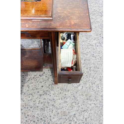 138 - Antique Oak sewing table containing a Jones sewing machine