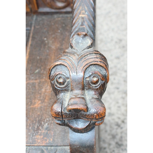 89 - Antique carved oak settle profusely carved with masks and foliage, 4 carved back panels depicting a ... 