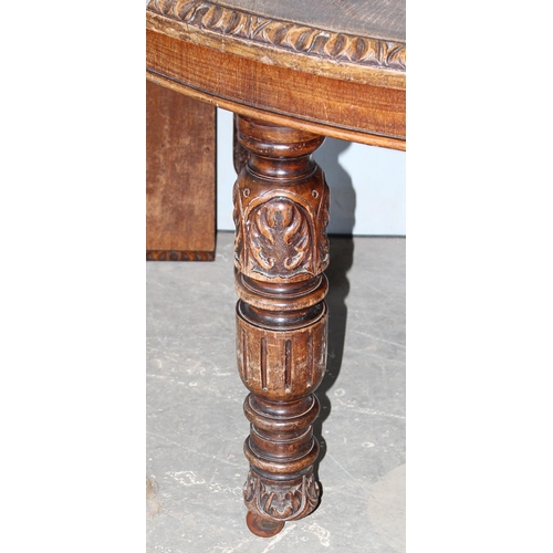 99 - A large antique carved oak dining table on impressive carved legs, extra leaf and original winder