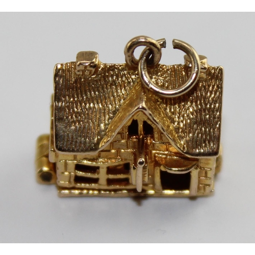 1220 - A 9ct gold charm of a house, opens to reveal a scene of domestic life, approx 4.61g gross weight