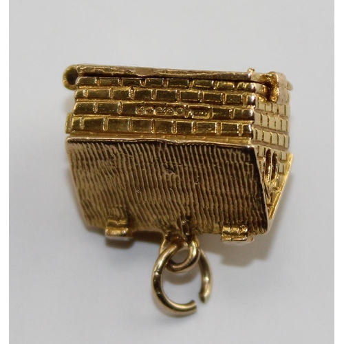 1220 - A 9ct gold charm of a house, opens to reveal a scene of domestic life, approx 4.61g gross weight