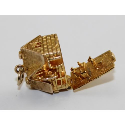 1220 - A 9ct gold charm of a house, opens to reveal a scene of domestic life, approx 4.61g gross weight