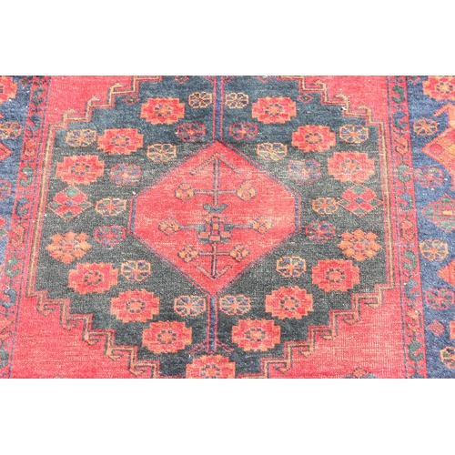 201 - A vintage handmade red & blue ground rug with central medallion, approx 220cm x 163cm