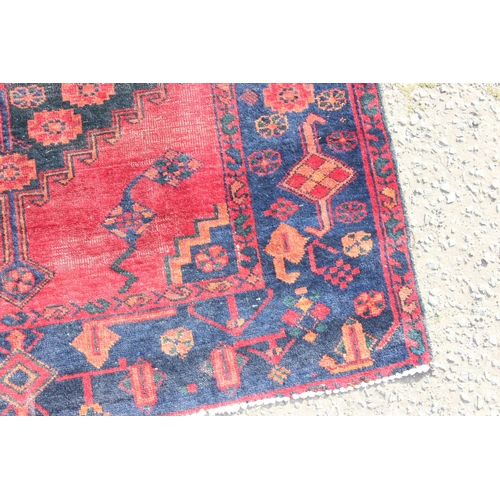 201 - A vintage handmade red & blue ground rug with central medallion, approx 220cm x 163cm