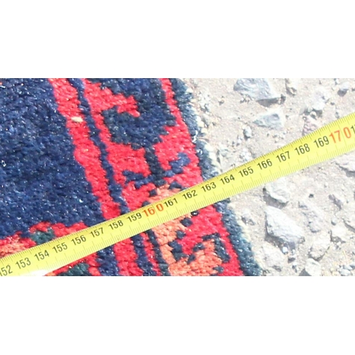 201 - A vintage handmade red & blue ground rug with central medallion, approx 220cm x 163cm