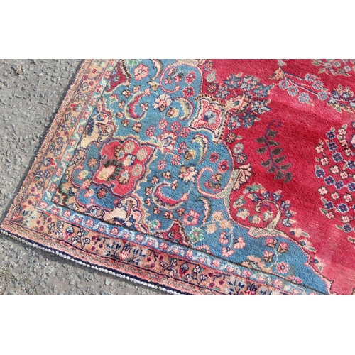 202 - A large Persian handmade rug of red ground with large central medallion, labelled verso, approx 309c... 