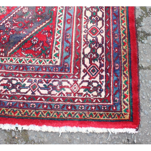 207 - A large decorative Iranian rug of red ground decorated with various geometric patterns, approx 309cm... 