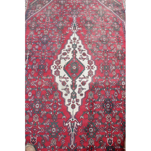 207 - A large decorative Iranian rug of red ground decorated with various geometric patterns, approx 309cm... 